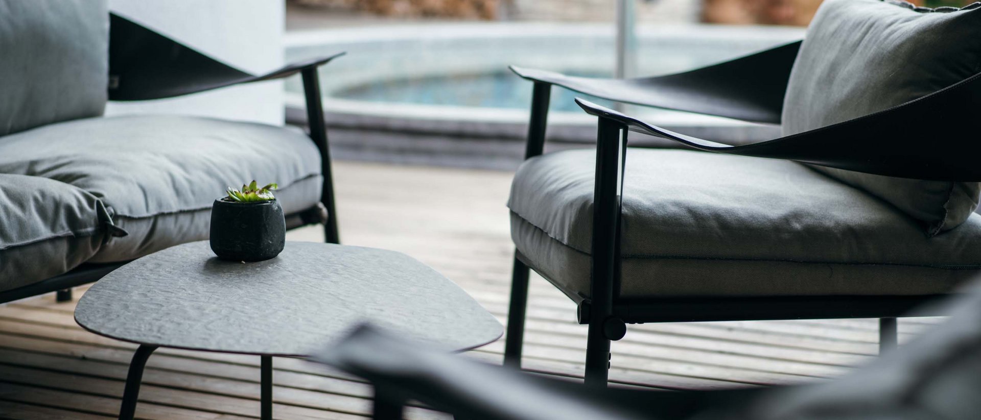 Set di sedute moderno con poltrone grigie e tavolino su terrazza in legno