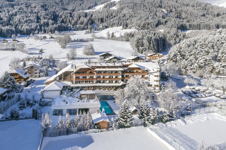 Hotel in snowy mountain landscape with surrounding trees and fields