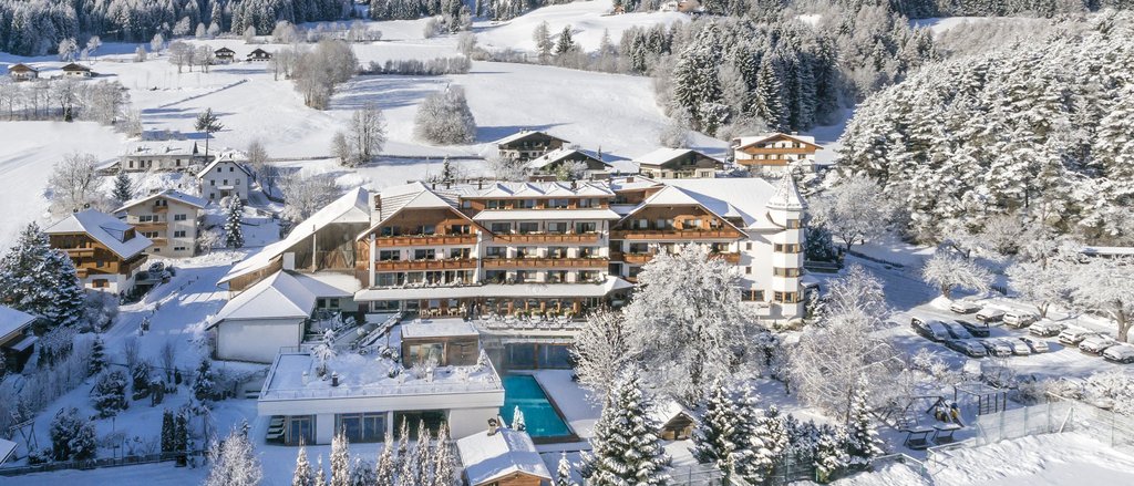 Der facettenreiche Spa unseres Spa-Hotels in Südtirol Hotel in verschneiter Berglandschaft mit umliegenden Bäumen und Feldern