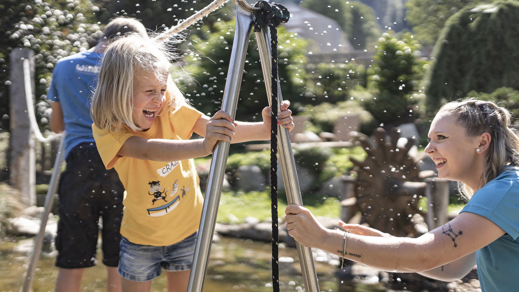 Bambina e donna ridono giocando con l'acqua all'aperto in una giornata di sole