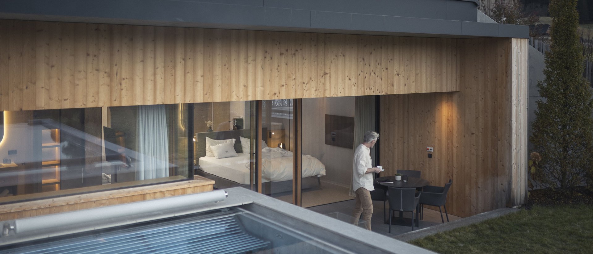 Your source of enrichment: our hotel at Mt Plan de Corones Man on terrace in front of modern wooden house with swimming pool