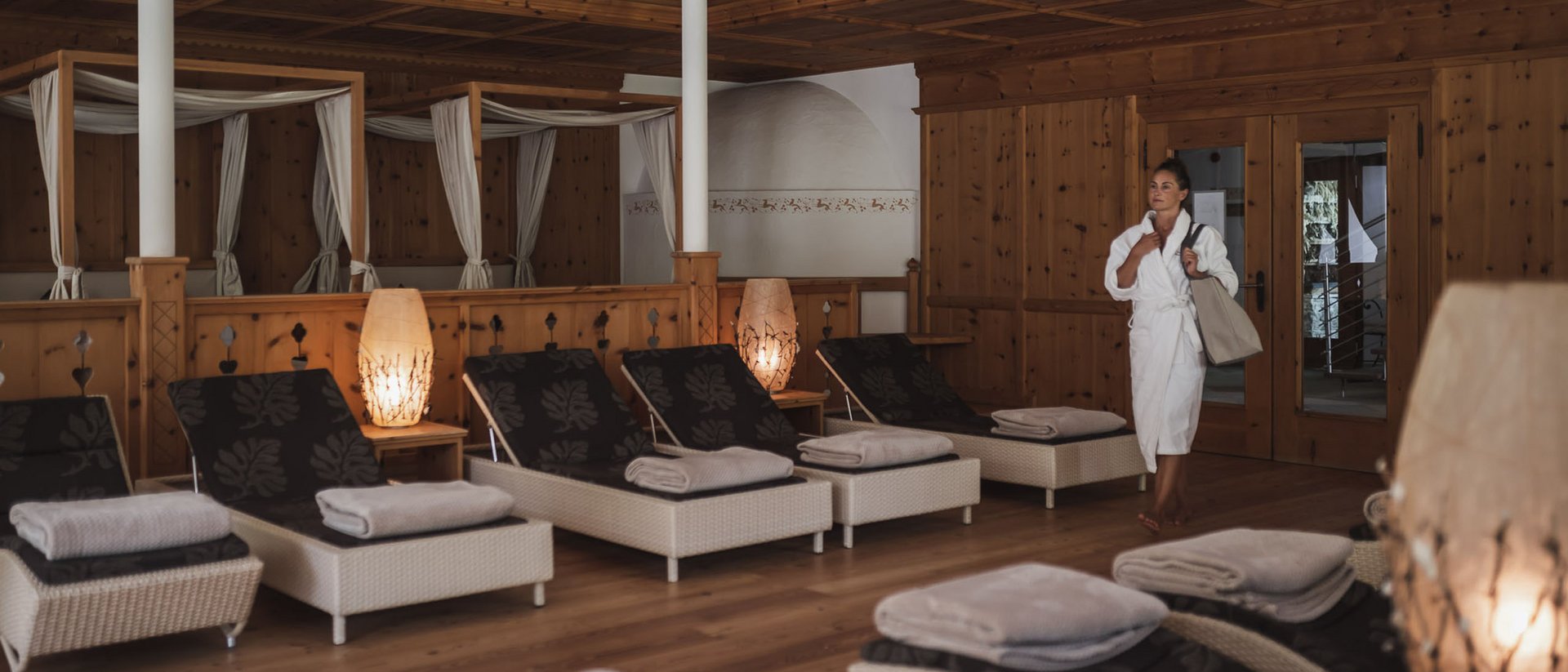 Frau im Bademantel in einem Spa-Ruheraum mit Liegen und gedämpfter Beleuchtung
