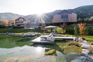 Modern wooden houses by a lake with sun rays in a mountain landscape