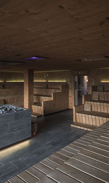 Grande sala in legno con camino di pietra riscaldato in sauna moderna