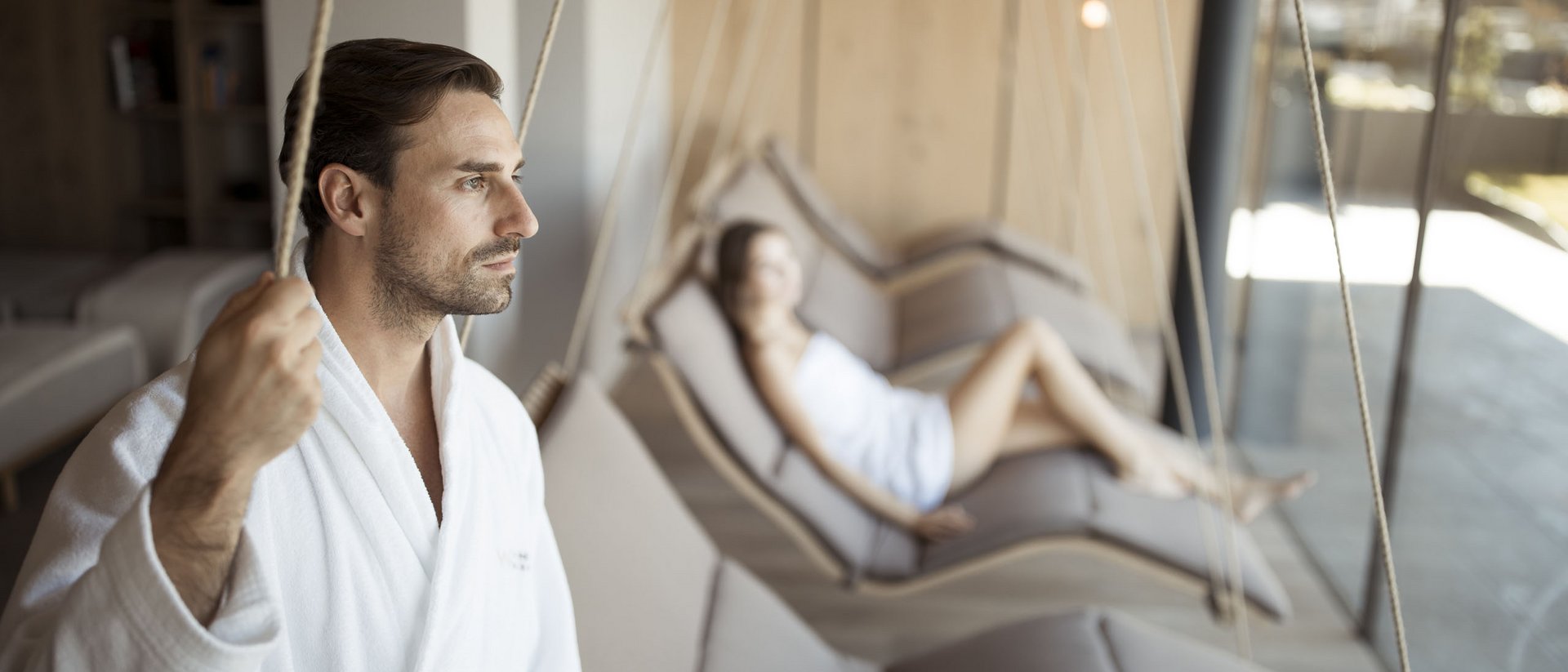 Uomo e donna si rilassano in accappatoi su poltrone sospese in una spa