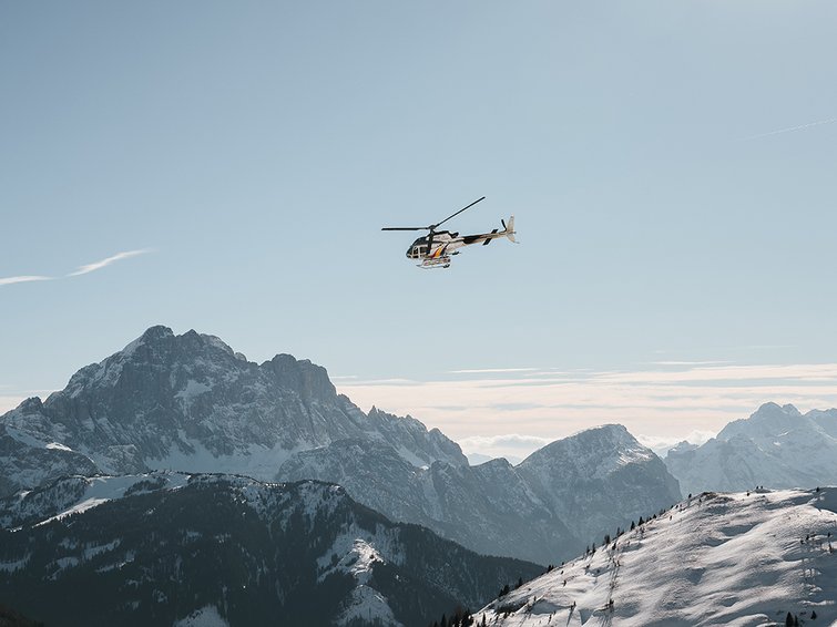 Elicottero vola sopra montagne innevate sotto cielo limpido