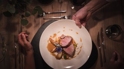 The best photos from our hotel in South Tyrol that kids love Hand serving a plate with meat and sauce at a set dining table