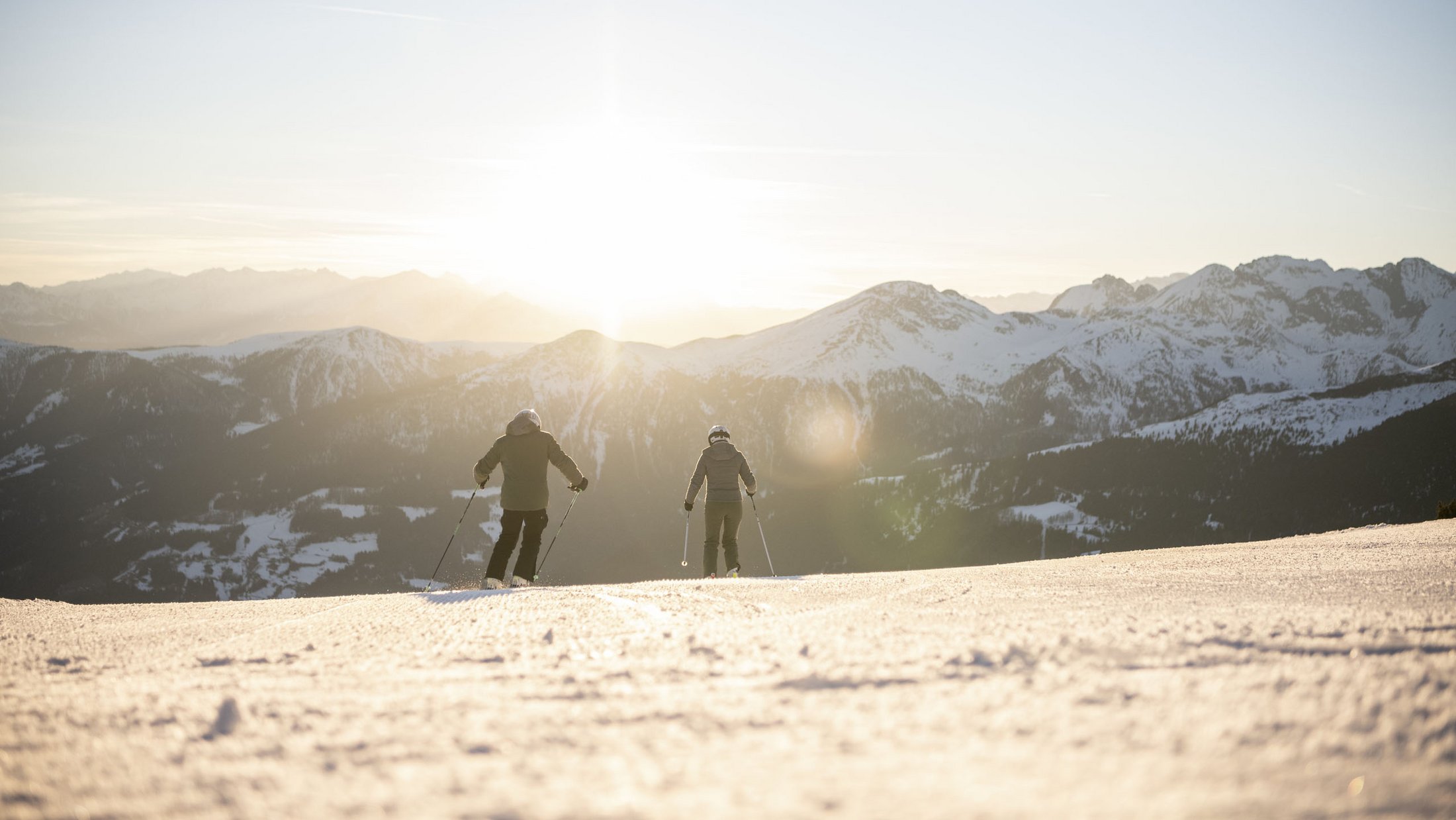 Hotel sulle piste del Plan de Corones: divertimento senza fine Due sciatori sulla pista innevata al tramonto in montagna