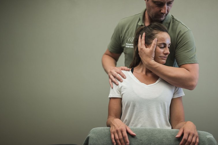 Physiotherapeut behandelt Frau mit manueller Nacken- und Schultertherapie