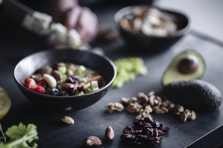 Schalendiät mit Nüssen, Beeren, Avocado und frischem Obst auf dunklem Tisch
