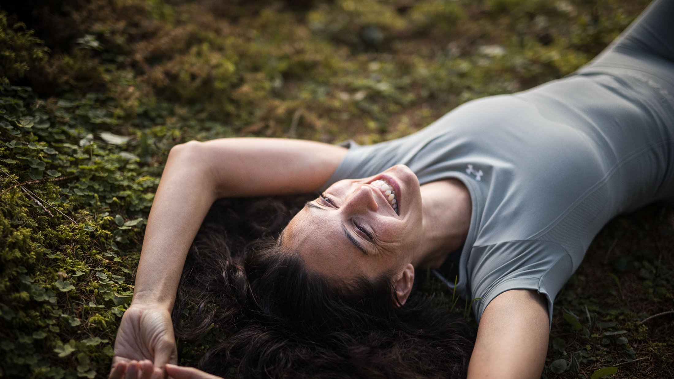 Donna sorridente sdraiata sull'erba con le braccia distese