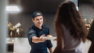 Photos from your hotel in Pfalzen in Val Pusteria/Pustertal Man in chef outfit handing a plate of food to a woman