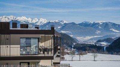 The best photos from our hotel in South Tyrol that kids love Modern building with balcony overlooking snowy mountains and valley