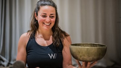 Donna sorridente tiene in mano una ciotola sonora e un battente