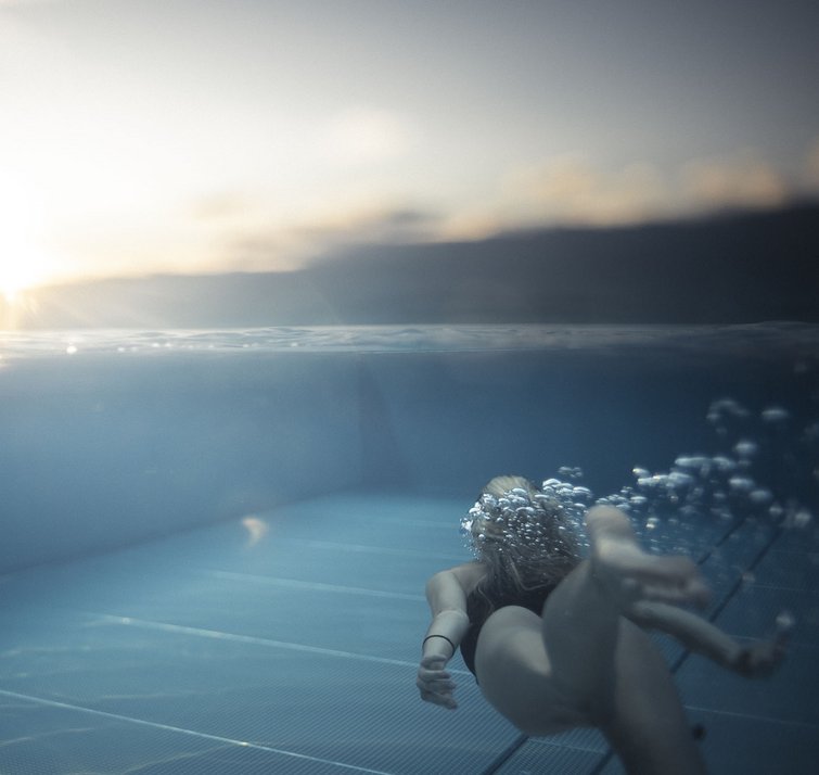 Persona che nuota sott'acqua in piscina al tramonto