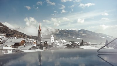 Snow-covered village with church and mountains under a blue sky