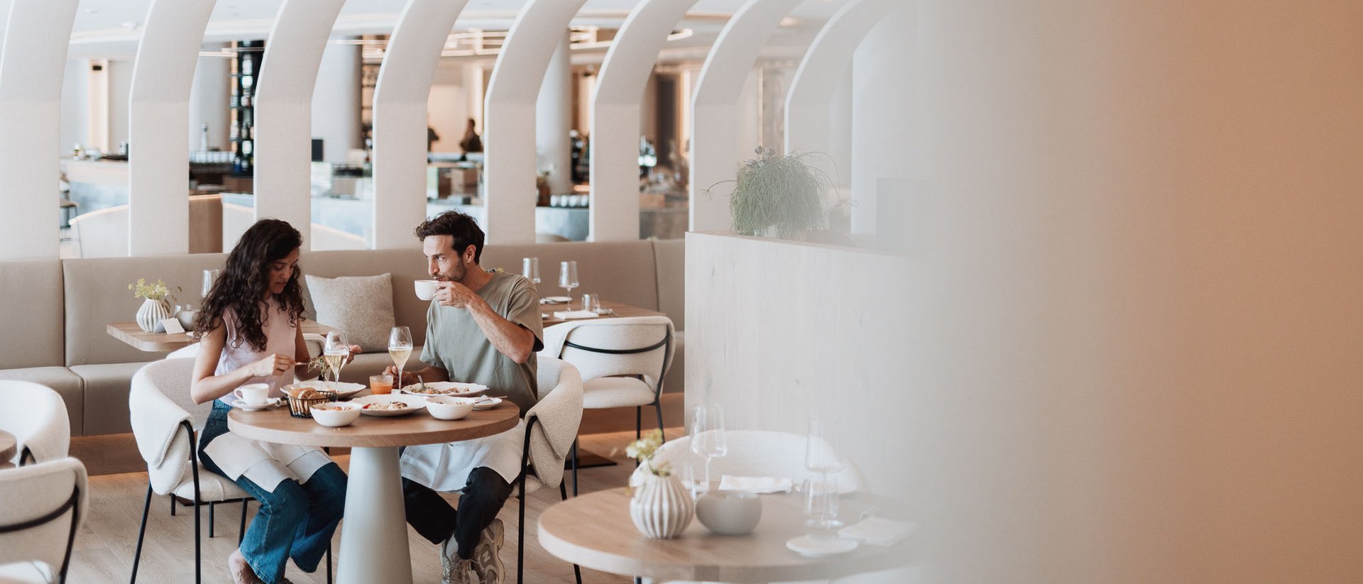 Paar isst und trinkt in modernem Restaurant mit gebogenen weißen Deckenbögen