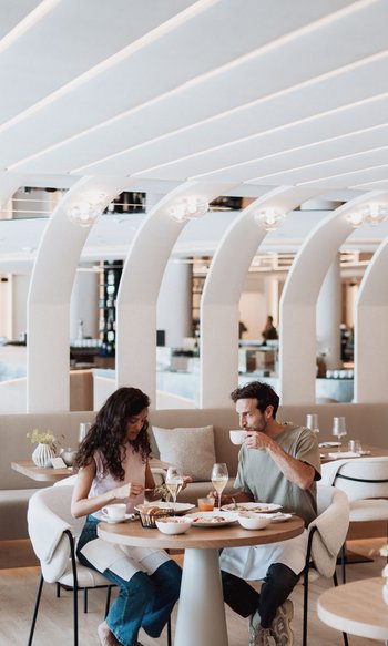 Paar isst und trinkt in modernem Restaurant mit gebogenen weißen Deckenbögen