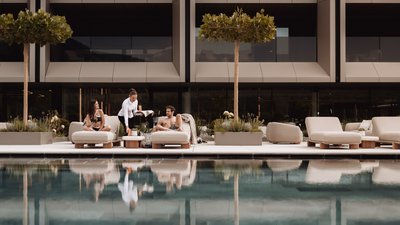 Photos from your hotel in Pfalzen in Val Pusteria/Pustertal Couple relaxing on loungers by pool, waitress serving drinks