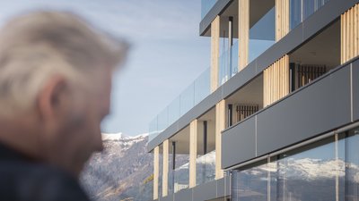 Complesso residenziale moderno con vista sulle montagne e uomo anziano sfocato