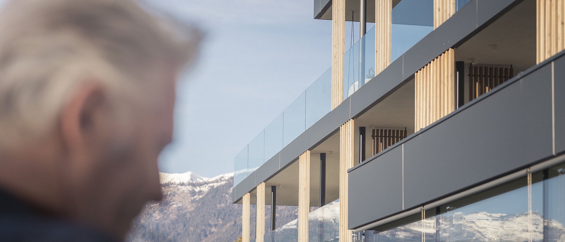 Modern residential building with mountain view and blurred elderly man