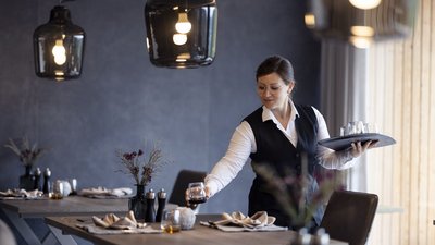 L’esclusività in foto: il nostro chalet in Alto Adige di lusso Cameriera sistema un bicchiere in un ristorante accogliente con arredamento moderno