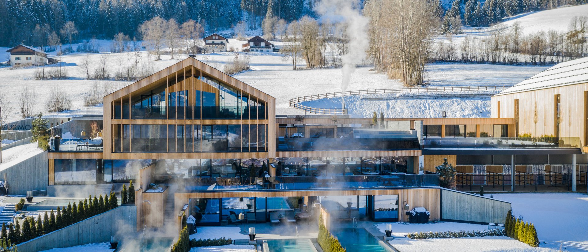 An enriching holiday in your luxury chalet in South Tyrol Modern spa hotel with heated outdoor pools in snowy mountain landscape