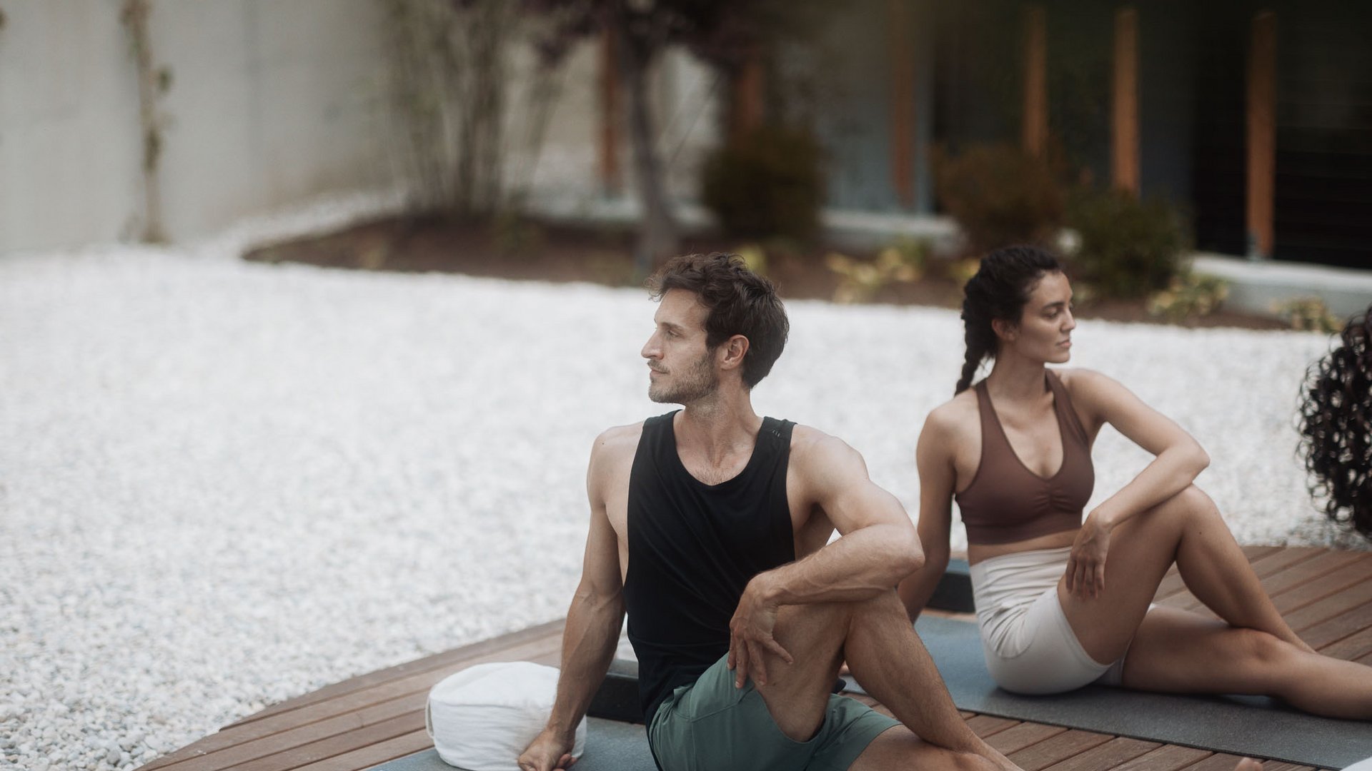 Uomo e donna fanno yoga all'aperto su tappetini su una pedana in legno