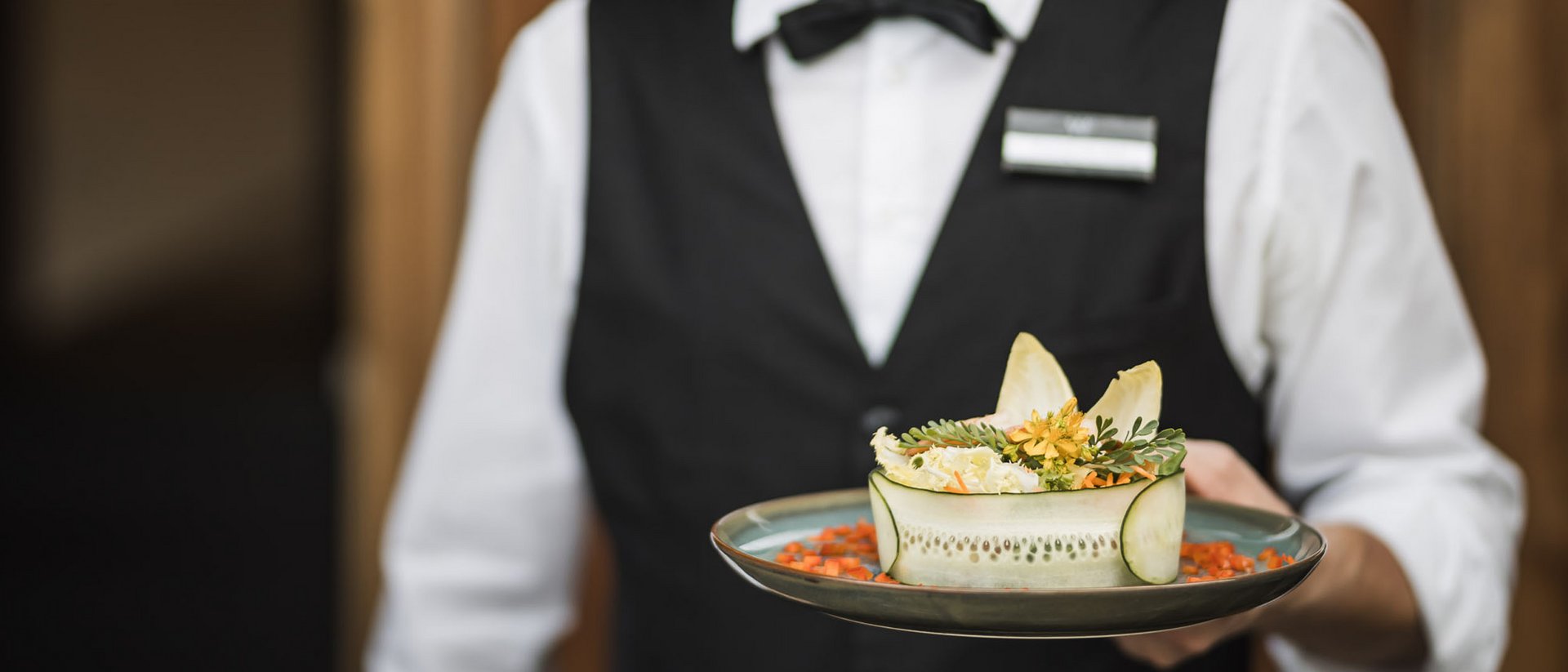 Kellner präsentiert kunstvoll angerichteten Salat auf Teller