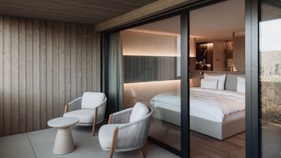 Photos from your hotel in Pfalzen in Val Pusteria/Pustertal Modern balcony with two chairs and view into a cozy bedroom