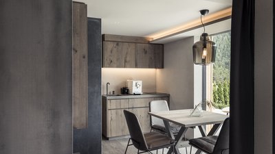 L’esclusività in foto: il nostro chalet in Alto Adige di lusso Zona pranzo moderna con tavolo in legno, sedie e angolo cucina dai toni neutri