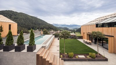 L’esclusività in foto: il nostro chalet in Alto Adige di lusso Corte moderna con edifici in legno, piscina e vista sulle montagne boschive