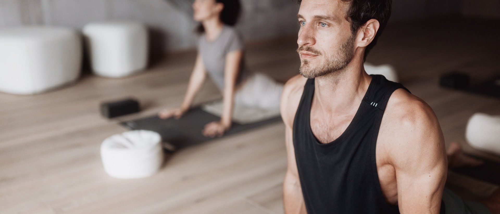 Man and woman practicing yoga in bright room on mats