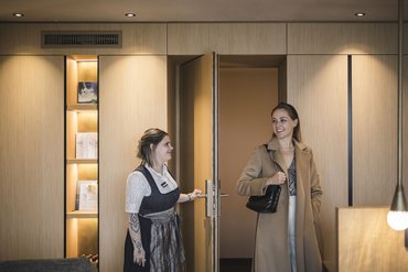 Hotel staff opening door for a woman wearing a coat