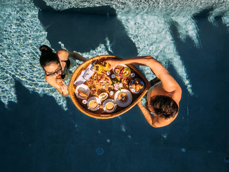 Due persone gustano colazione con caffè e dolci in piscina