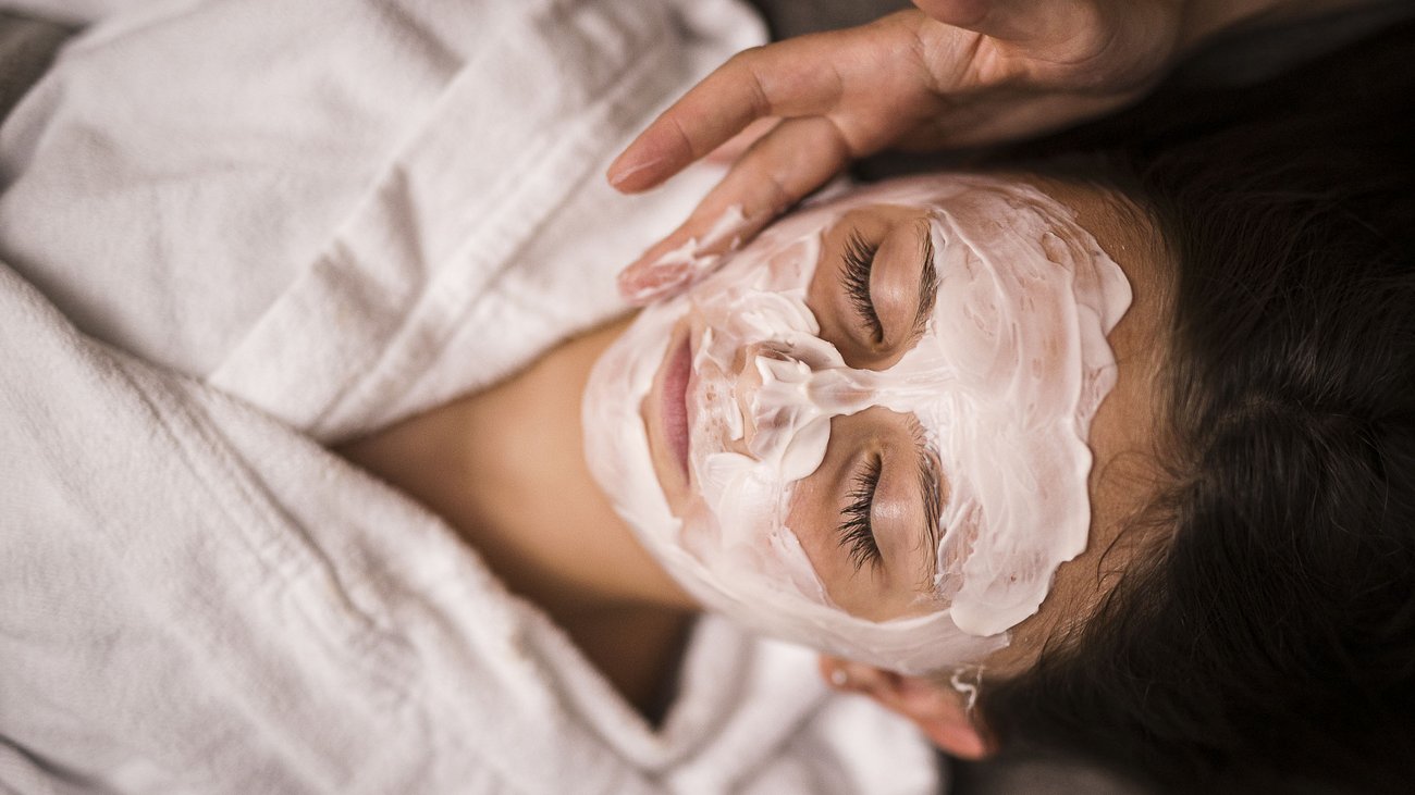 Frau bei Gesichtspflege mit Creme in Spa entspannt