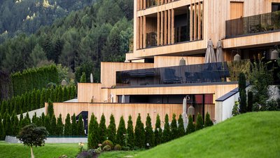 L’esclusività in foto: il nostro chalet in Alto Adige di lusso Casa moderna in legno con balconi in vetro ai piedi di una montagna verde