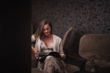 Donna legge un libro in una stanza accogliente con poltrone comode