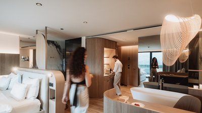 Photos from your hotel in Pfalzen in Val Pusteria/Pustertal Modern hotel room with bathtub, sleeping area, and two people