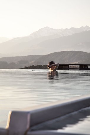 Person swimming in infinity pool with mountain view