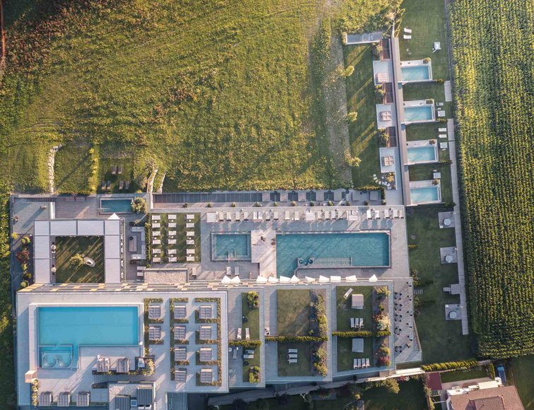 Vista aerea di un resort con diverse piscine, lettini e campi adiacenti