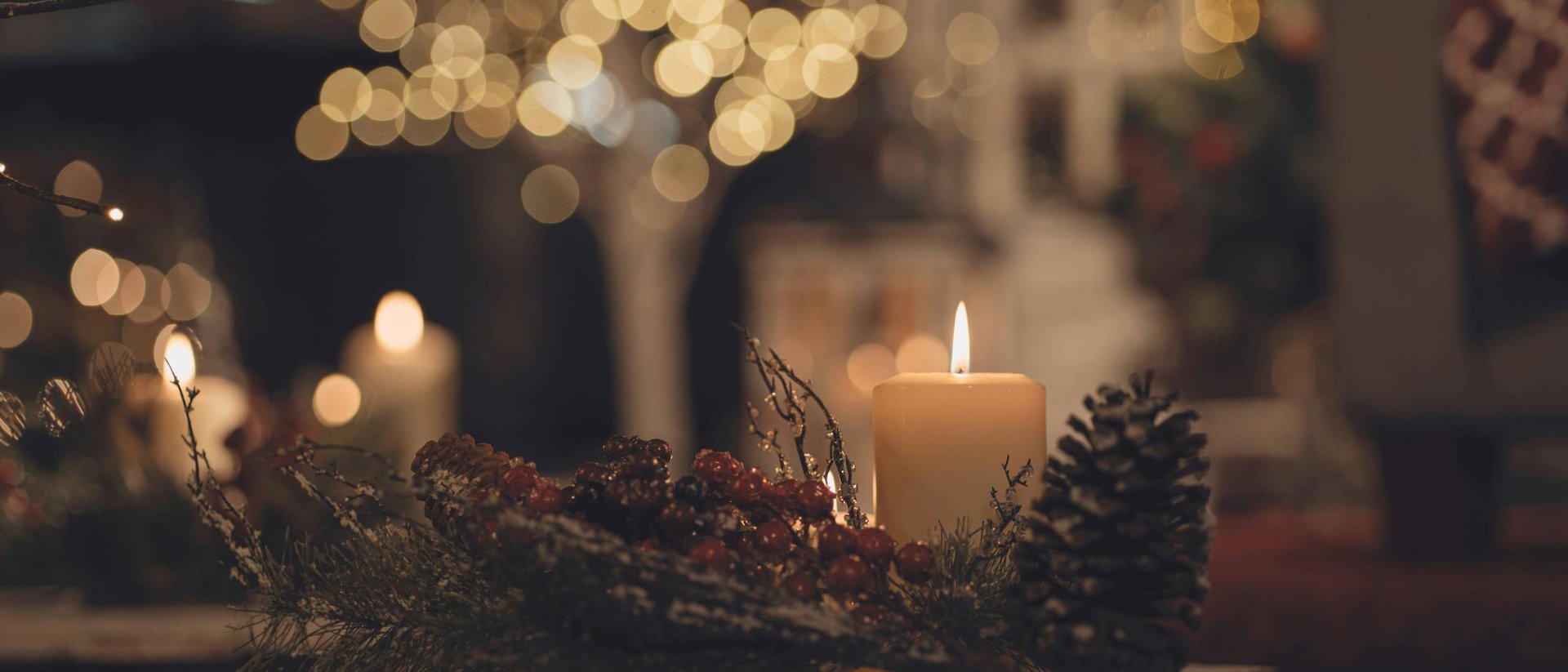 Candela accesa con pigna e bacche come decorazione natalizia