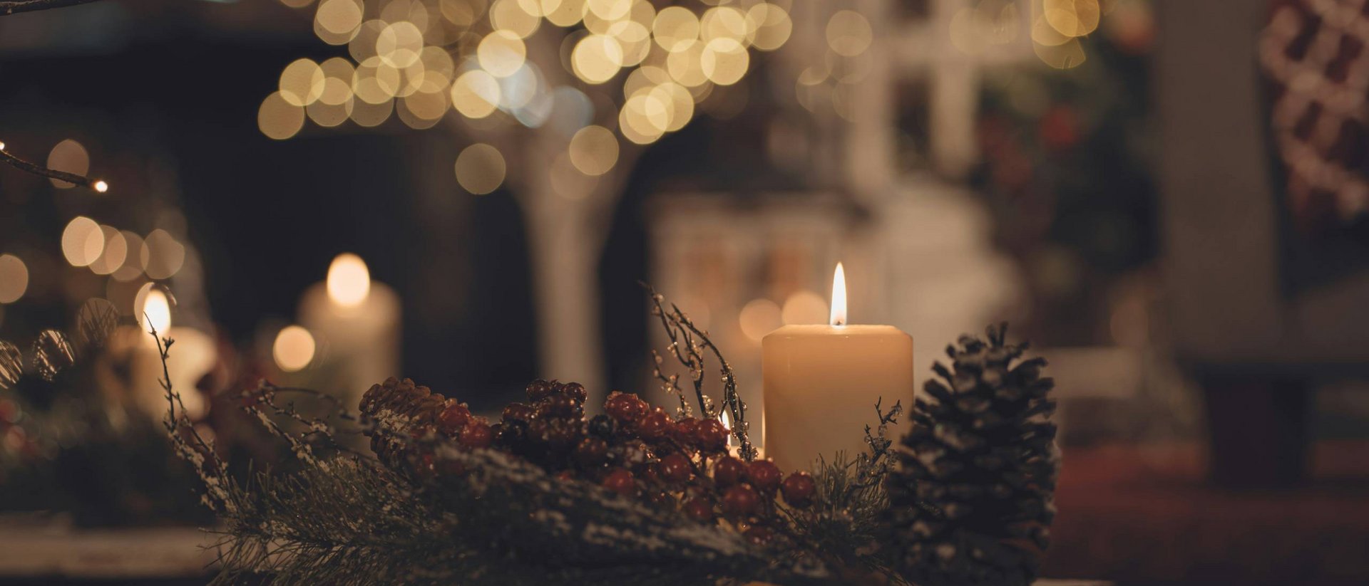 Brennende Kerze mit Tannenzapfen und Beeren als weihnachtliche Dekoration