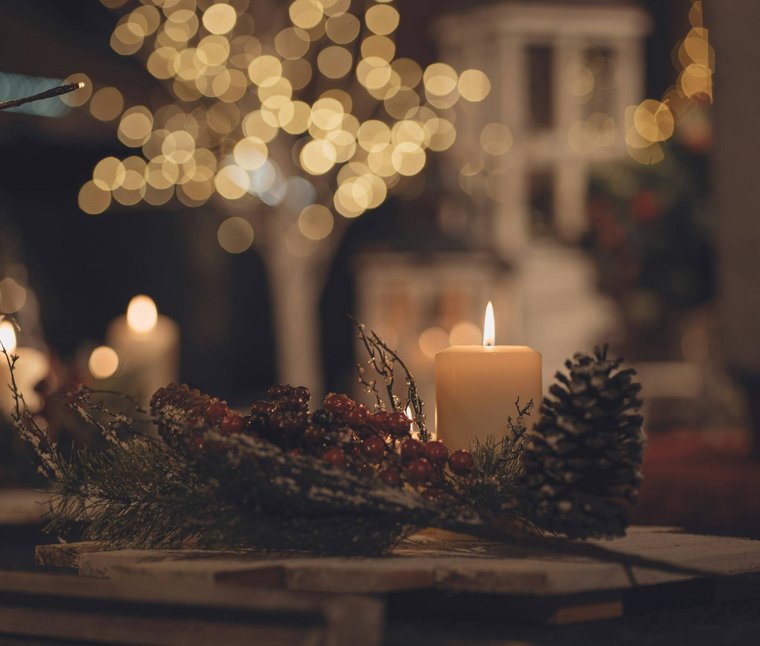 Candela accesa con pigna e bacche come decorazione natalizia