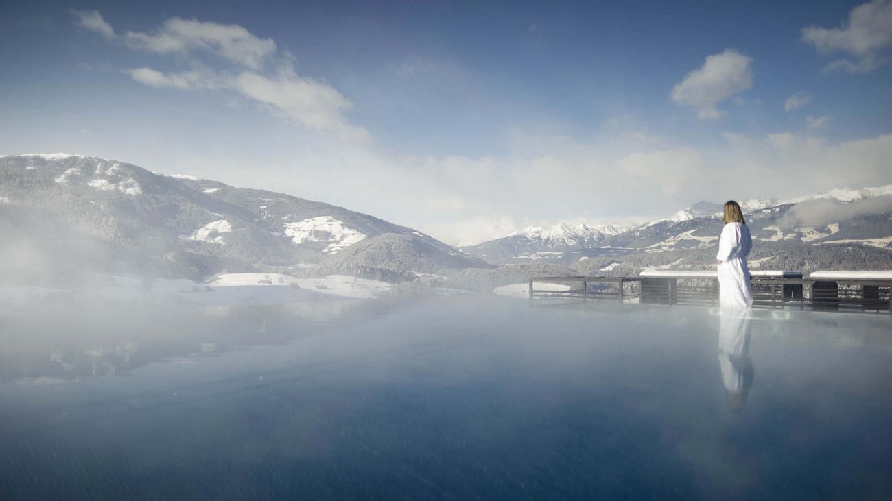 Hotel Solvie: Day Spa der Extraklasse Frau in Bademantel am beheizten Außenpool mit Blick auf schneebedeckte Berge