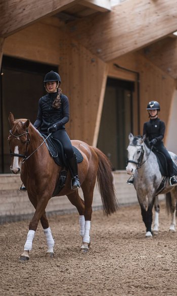 Lezione di equitazione con tre bambini a cavallo e un istruttore in una scuderia