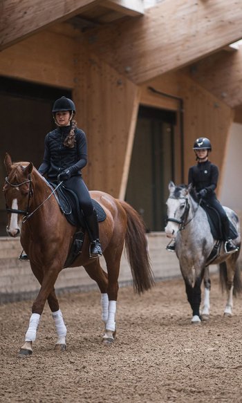 Horse riding lesson with three children on horses and an instructor in an indoor arena