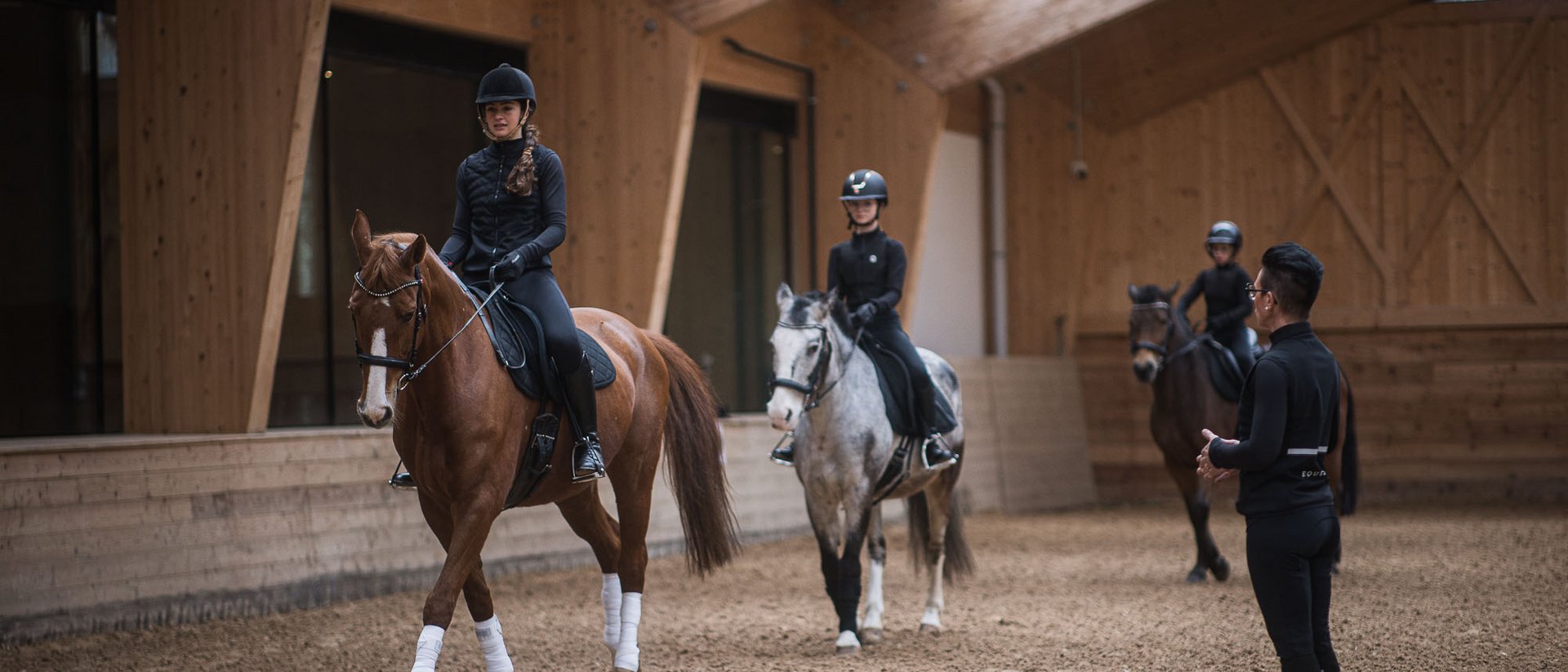 Dove fare equitazione in Alto Adige: hotel con maneggio Lezione di equitazione con tre bambini a cavallo e un istruttore in una scuderia