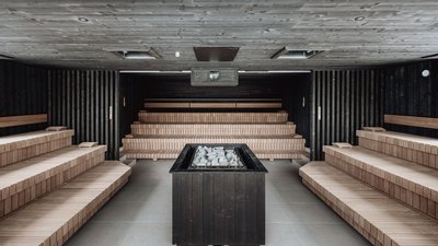Interior of a modern sauna with wooden benches and central stone heater