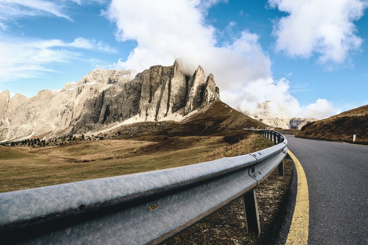 Mountain landscape with winding road and metal guardrail in the foreground